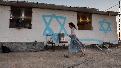 A young woman walks past a simple housing unit in the settlement of Givat Evyatar, West Bank, a luglio 1.