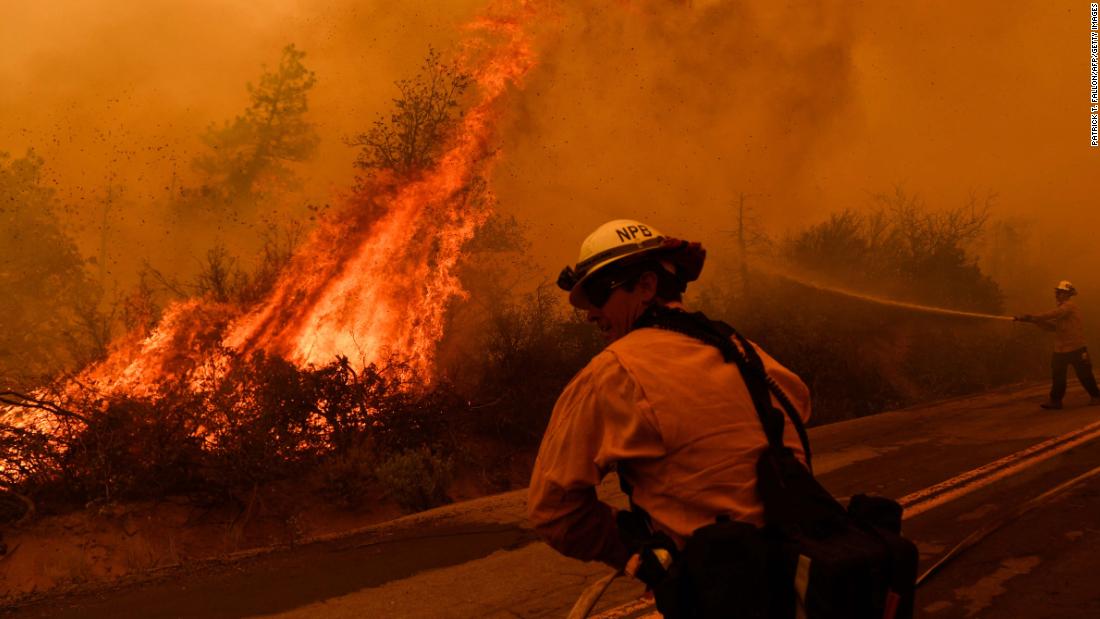 Los bomberos rocían agua mientras las llamas del Windy Fire empujan hacia una carretera en California&#39;s Bosque Nacional Sequoia en septiembre 22.