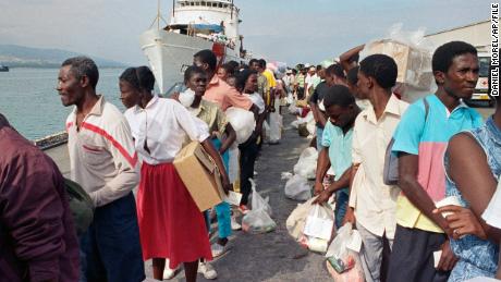 Haitian refugees disembark from a US Coast Guard vessel in February 1992 after being  deported from Guantanamo Bay, Cuba.