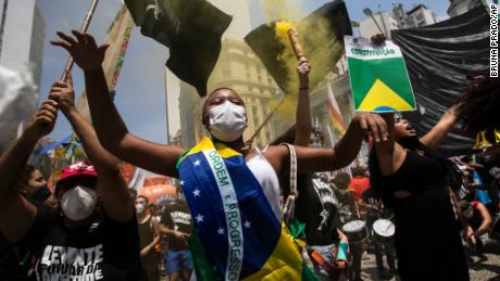 A woman, wrapped in a Brazilian national flag, chants slogans during a protest against Brazilian President Jair Bolsonaro on Saturday, October 2. 
