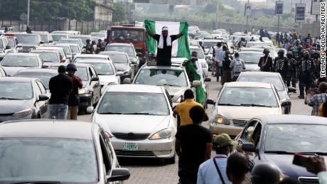 A demonstrator raises a Nigerian flag from a car during a motorcade to mark the one-year anniversary of the #EndSARS protest at the Lekki toll gate on Wednesday.