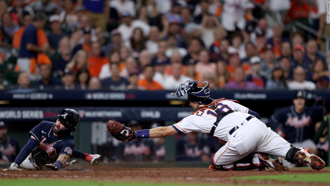 Die Braves&#39; Dansby Swanson slides in safely past the Astros&#39; Jason Castro to score a run on a sacrifice fly during the eighth inning in Game 1.