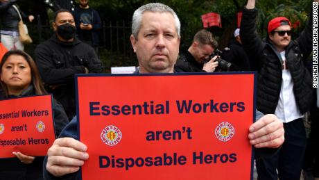 A protester at Thursday&#39;s rally holds a sign that reads, &quot;Essential Workers aren&#39;t Disposable Heros.&quot; 