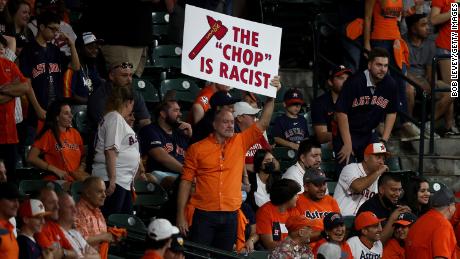 A fan holds a sign stating &quot;the chop is racist&quot; during the ninth inning in Game One of the 2021 World Series at Minute Maid Park in Houston.