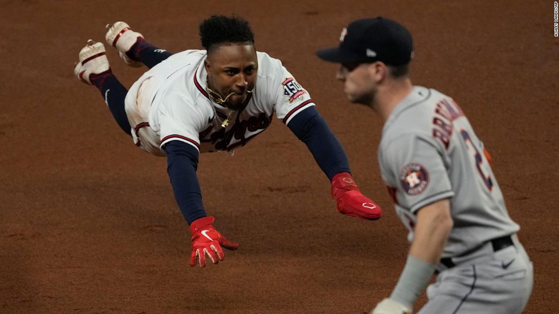 Braves second baseman Ozzie Albies dives into third past Astros third baseman Alex Bregman advancing on a double by Austin Riley on Sunday.