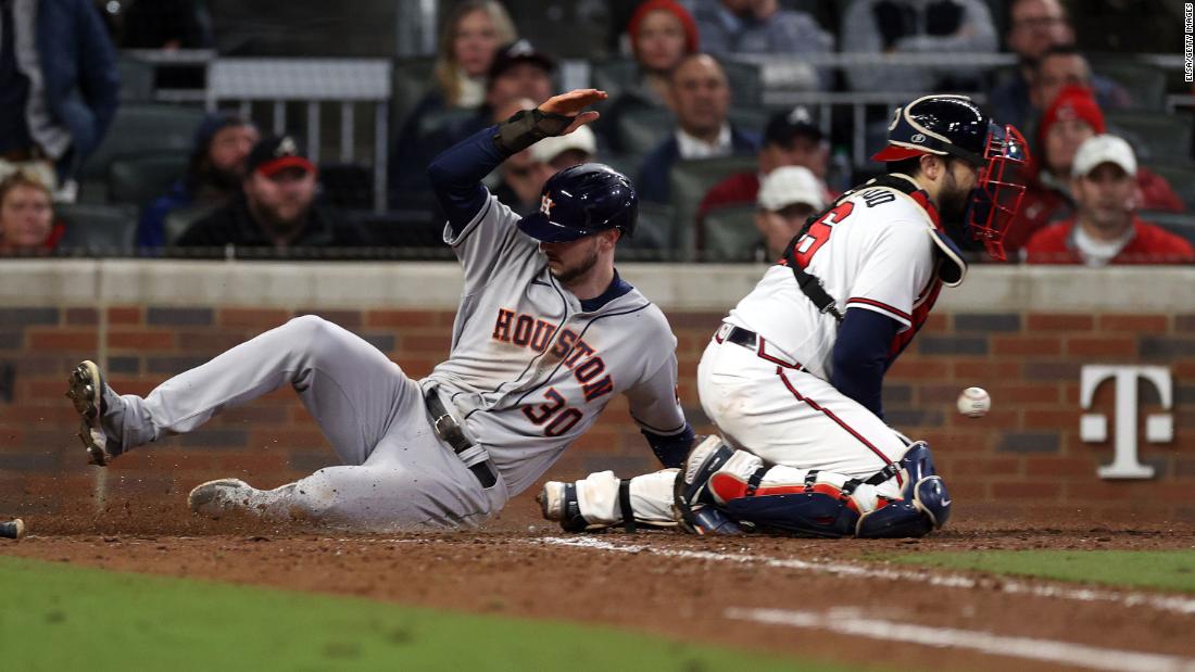 Houston Astros right fielder Kyle Tucker slides into home plate safely past Braves catcher Travis d&#39;Arnaud during the seventh inning.