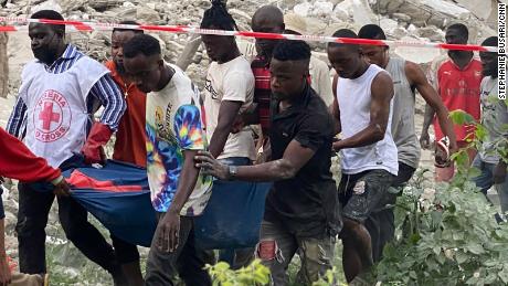Red Cross Nigeria officials and locals carry a body from rubble in Lagos.