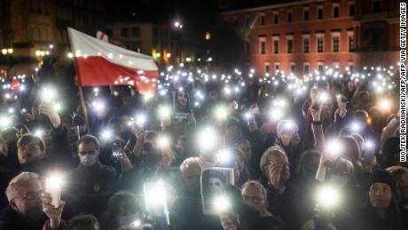 Protesters hold up lights, a Polish flag and a photograph of Iza as they take part in a demonstration on November 6, 2021 in Warsaw.