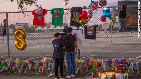Concert attendees Isaac Hernandez and Matthias Coronel watch Jesus Martinez sign a remembrance board at a makeshift memorial on November 7, 2021 at the NRG Park in Houston