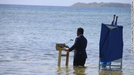 तुवालु के विदेश मंत्री समुद्री जल में घुटने के बल खड़े हैं, यह बताने के लिए कि किस प्रकार जलवायु परिवर्तन से समुद्र का स्तर बढ़ रहा है।