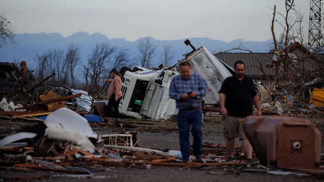 People stand among the debris in Mayfield.
