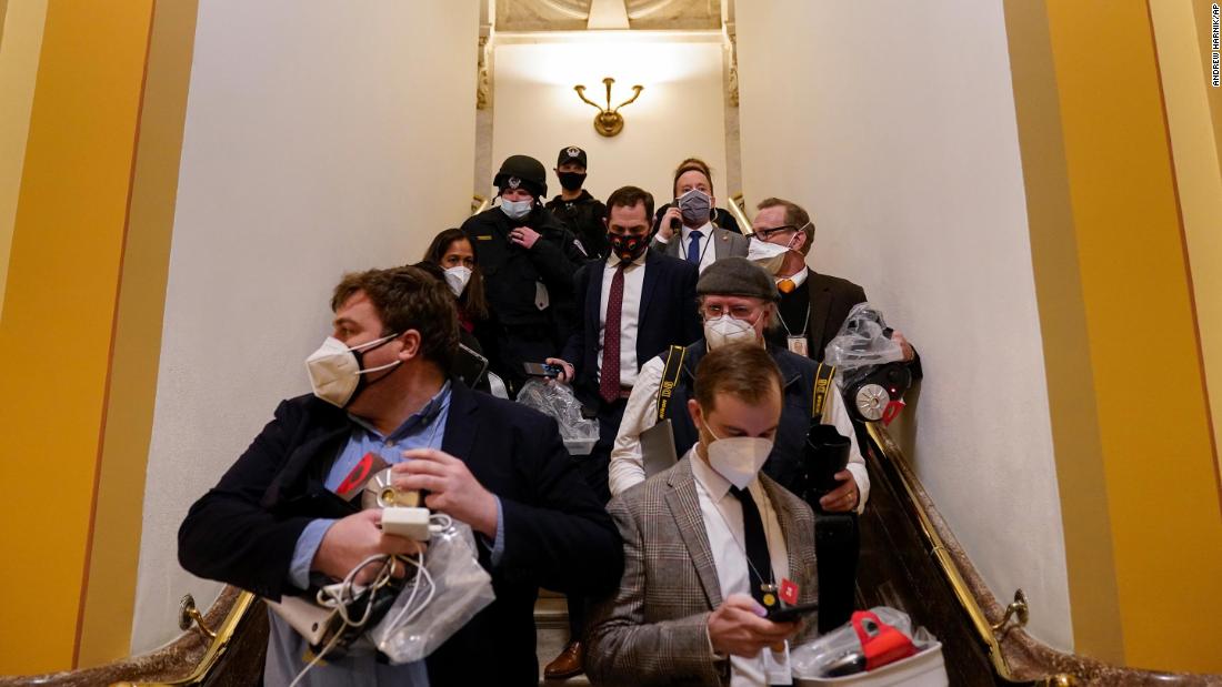 People evacuate the House chamber as rioters attempt to break in.