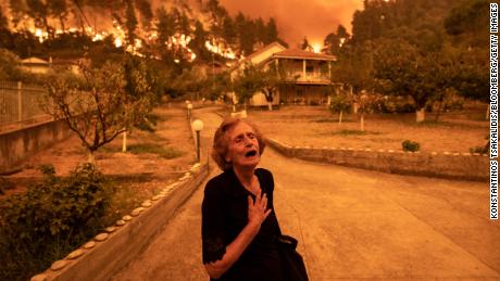 An elderly woman is forced from her home as a wildfire bears down on the island of Evia, 希腊, 在八月.