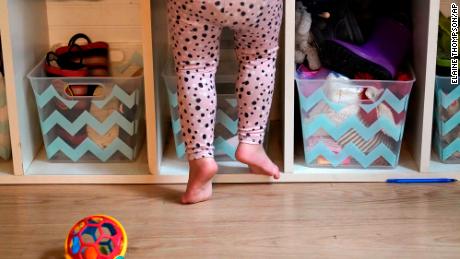 A preschooler gets up on her toes to reach into her cubby at a preschool center in Mountlake Terrace, Washington. 