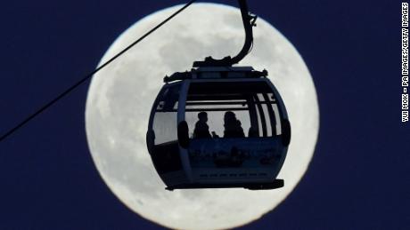 A cable car passes in front of the moon as it crosses the River Thames in London on Monday, 일월 17.
