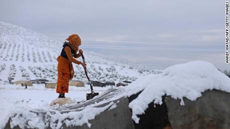 A woman shovels snow off her tent at a camp for internally displaced people in Raju, 叙利亚. 