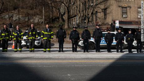 New York City police officers and firemen stand at attention as they await the remains of Police Officer Jason Rivera to be brought to the funeral home on January 23 뉴욕시. 