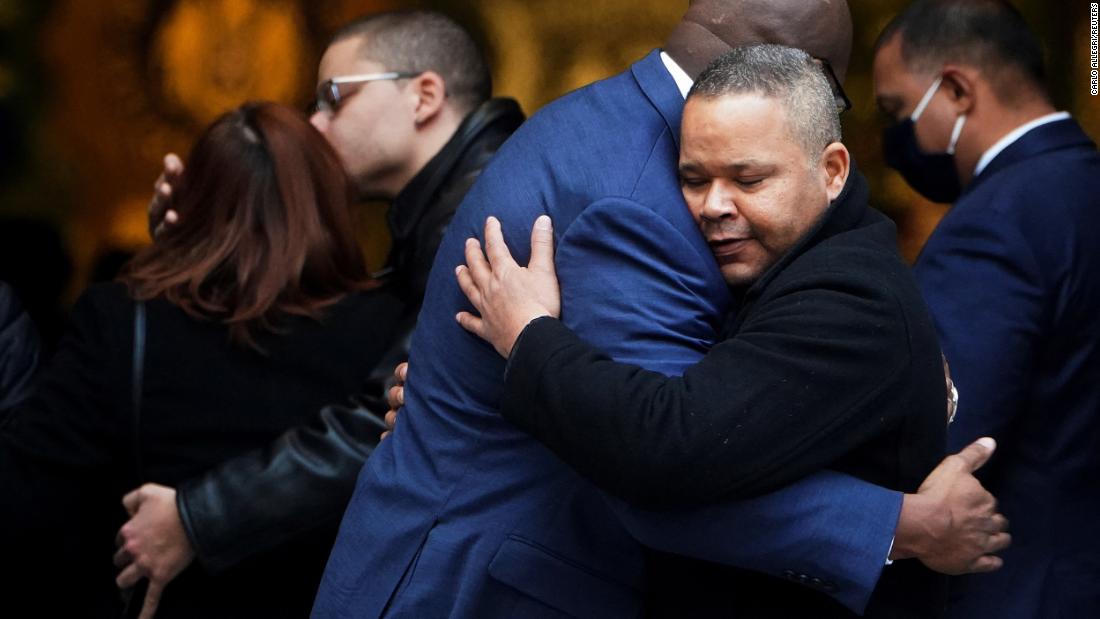Friends and family hug at Rivera&#39;葬儀中にリベラの写真を持っている男性.