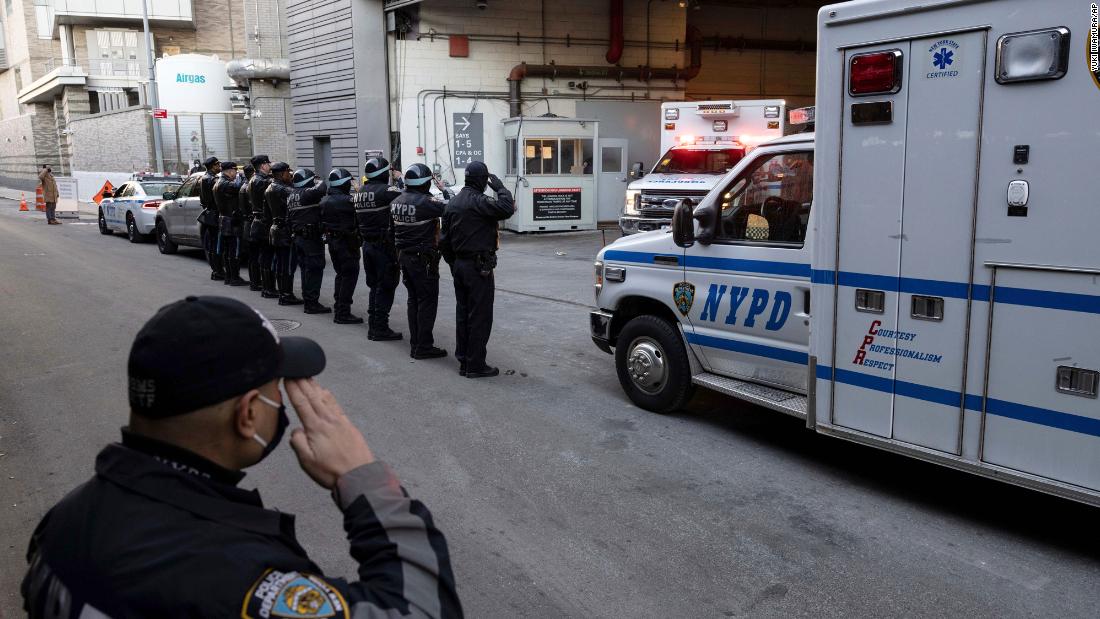 Police officers salute as Mora&#39;s remains are transferred outside a New York City hospital on Tuesday, January 25.