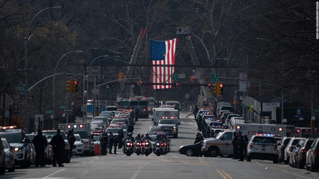 A procession for Rivera&#39;火曜日にモラの遺体がニューヨーク市の病院の外に移送されると、警察官が敬礼する.