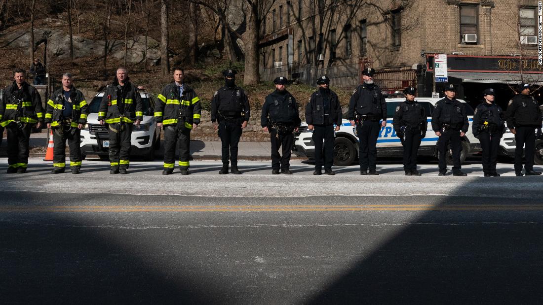 Police officers and firefighters stand at attention before Rivera&#39;s remains were brought to a funeral home on Sunday.