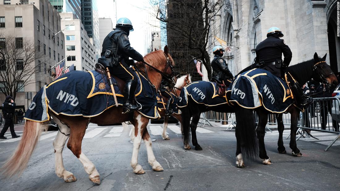 Police officers on horseback arrive outside St. パトリック&葬儀中にリベラの写真を持っている男性Thursday.