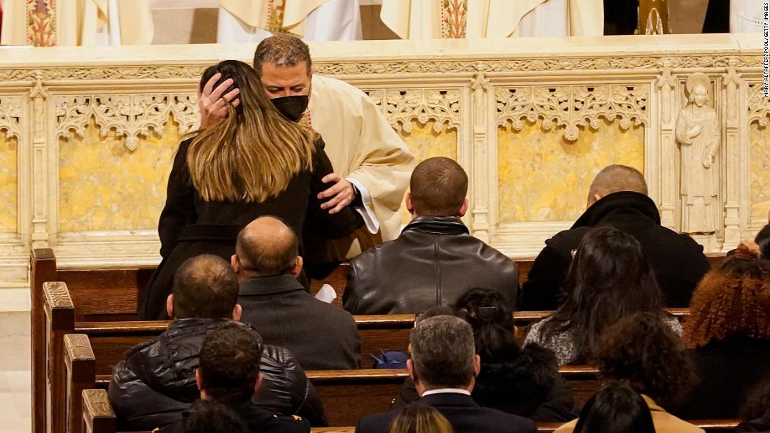 A priest hugs Rivera&#39;s wife, Dominique, on Friday.