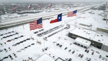 Flags fly over car dealerships as light traffic moves through snow and ice on Route 183 in Irving, Texas, on February 3.