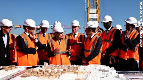 Paris Mayor Anne Hidalgo (씨) speaks past French President Emmanuel Macron (second L) during a visit of the building site of the Olympic Village in Saint-Ouen on October 14, 2021.