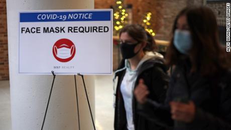 WASHINGTON, DC - DECEMBER 21:  People pass a sign that reads &quot;Face Mask Required&quot; in a mall as COVID-19 cases surge in the city on December 21, 2021 in Washington, DC. District of Columbia Mayor Muriel Bowser reinstated the city&#39;s indoor mask mandate at 6am on Tuesday and announced a vaccination mandate for government employees after COVID-19 case numbers have surged to a new high.  (Photo by Alex Wong/Getty Images)