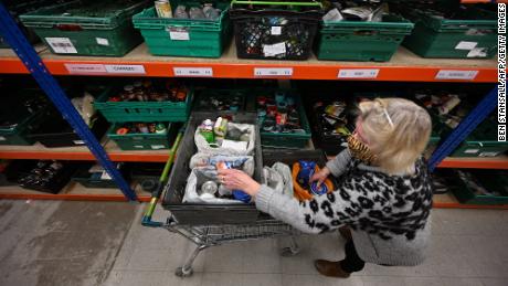 A volunteer collects donated items from shelving racks at a food bank in Colchester, England, on January 20.