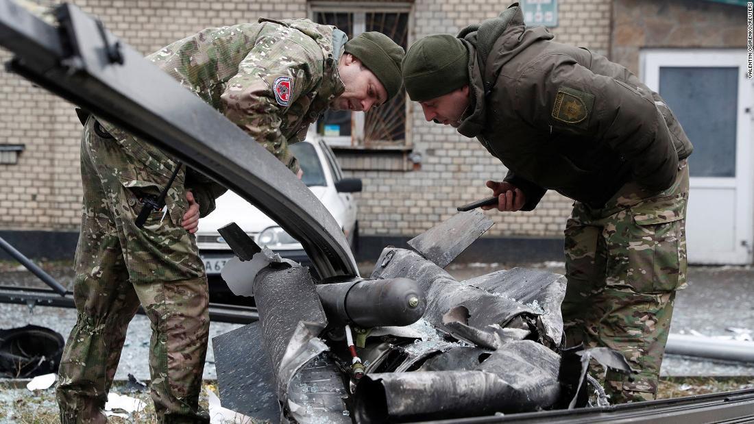 Police officers inspect the remains of a missile that landed in Kyiv on February 24.
