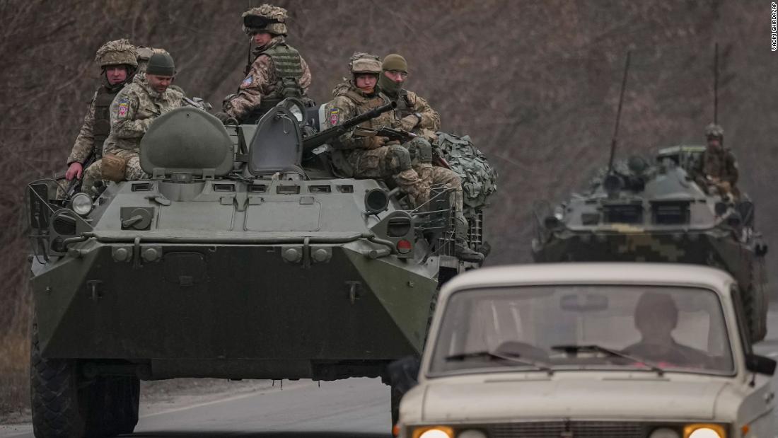 Ukrainian service members sit atop armored vehicles driving in eastern Ukraine&#39;s Donetsk region on February 24.