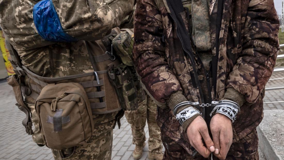 A Ukrainian serviceman stands with a handcuffed Russian soldier in Kharkiv on March 31.