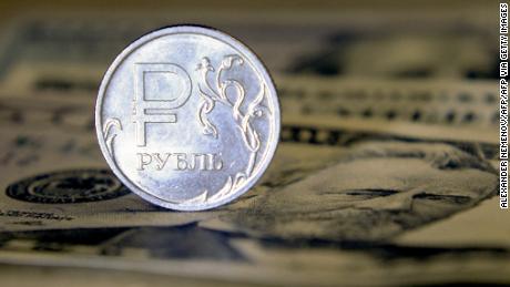 A Russian ruble coin is pictured with US dollar bills in Moscow, on August 23, 2018. - Russia&#39;s ruble hit its lowest level against the dollar for more than two years, a day after the latest round of punitive US sanctions took effect. The ruble&#39;s value dropped to 69 against the dollar for the first time since April 2016, when the shocks from the first Western sanctions over Russia&#39;s actions in Ukraine were still being felt. (Photo by Alexander NEMENOV / AFP) (Photo by ALEXANDER NEMENOV/AFP via Getty Images)