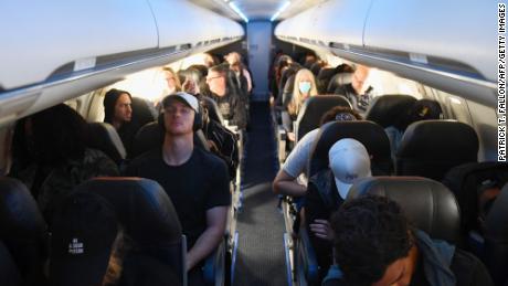 Airline passengers, some not wearing face masks following the end of Covid-19 public transportation rules, sit during a American Airlines flight operated by SkyWest Airlines from Los Angeles International Airport (LAX) in California to Denver, Colorado on April 19, 2022. Mask mandates on public transportation are no longer in effect following a ruling by federal judge on April 18, 2022. 