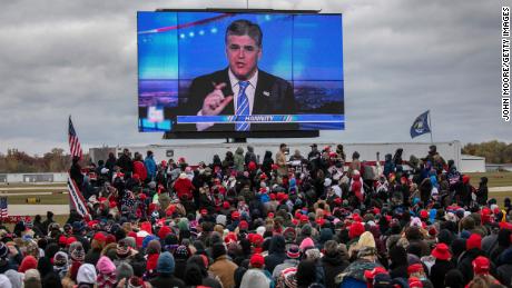 Supporters of President Donald Trump watch a video featuring Fox host Sean Hannity ahead of Trump&#39;s arrival to a campaign rally in Michigan on October 30, 2020.