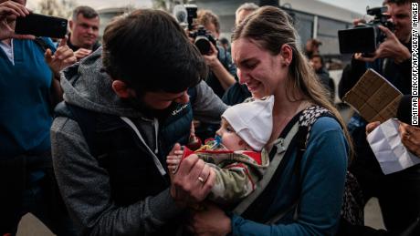 A man welcomes Anna Zaitseva and her 6-month-old son Svyatoslav at a registration and processing area for internally displaced people in Zaporizhzhia.