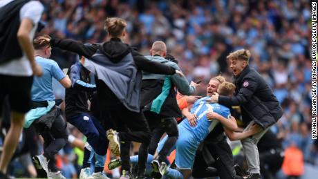 Kevin De Bruyne is mobbed by Manchester City fans after the club wins the Premier League.