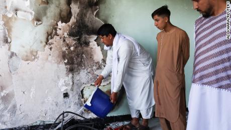 A man pours water on smouldering ashes inside a house damaged when an explosive-laden vehicle detonated amidst an attack on a Sikh temple in Kabul. 