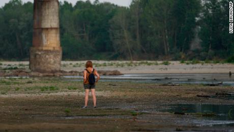 A woman stands on the Po riverbed next to Ponte della Becca (Becca bridge) in Linarolo, near Pavia, Italia, en Junio 27, 2022.