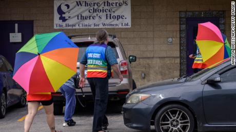 Volunteer clinic escorts shield a patient from anti-abortion demonstrators at the Hope Clinic For Women in Granite City, Illinois, en Junio 25, 2022. 