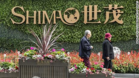An elderly couple walk past a sign in front of Shimao Tower, developed by Shimao Group Holdings Ltd., in Shanghai, Sjina, op Saterdag, Jan.. 8, 2022. 