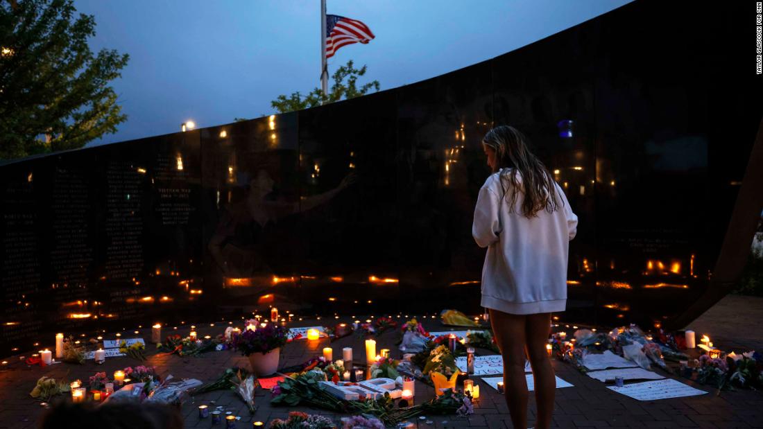  A woman views the candles and flowers left for the victims of the July 4th parade shooting on Tuesday, 칠월 5, 2022 in Highland Park, 일리노이.