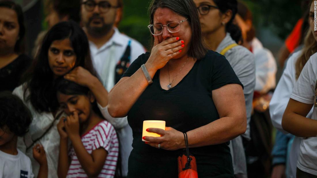 Elizabeth Zweiback cries during a candlelight vigil for the victims. Zweiback and her husband were marching in the parade with the Maureen Township food bank when the attack started. &quot;We ran for our lives,&quot; she said. 