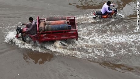 People drive across a flooded street after heavy rainfall in Lahore, Pakistan on July 21, 2022. 