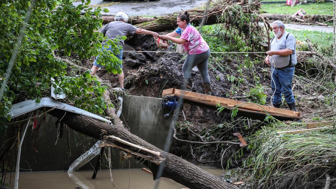 Tonya Smith reaches for food from her mother, Ollie Jean Johnson, to give to Smith&#39;の父, Paul Johnson, as they hang over a flooded Grapevine Creek in Perry County on Thursday. スミス&#39;s trailer was washed away; her father was staying the night in his home without power.