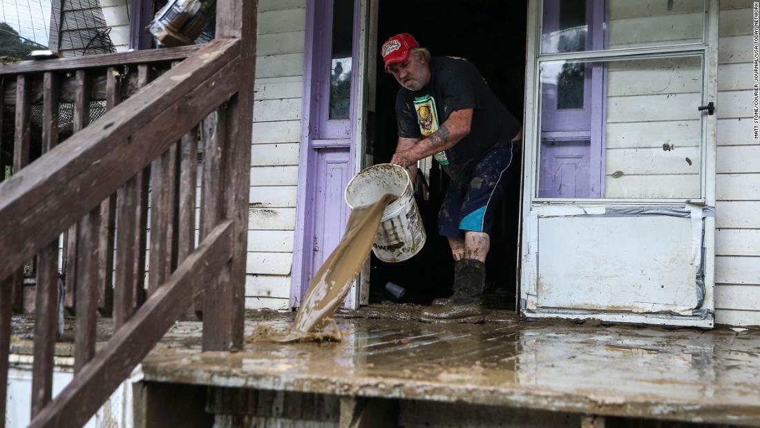 Terry Hatworth tries to wash the mud off Earl Wallen&#39;s porch in Garrett on Friday morning. The tiny town was without clean water.