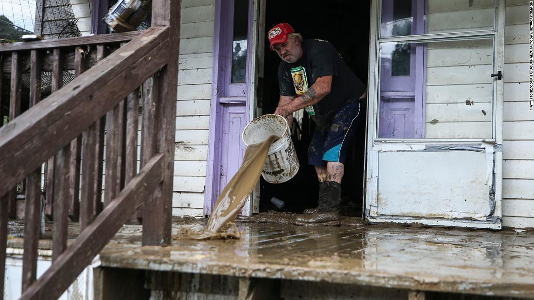 Terry Hatworth tries to wash mud off Earl Wallen&#39;s porch in Garrett, ケンタッキー, 金曜日に. The tiny town was without clean water.