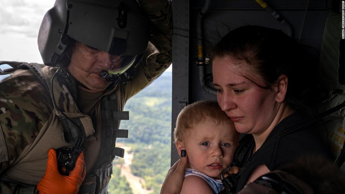 Command Sgt. Mei. Tim Lewis of the Kentucky National Guard secures Candace Spencer and her son Wyatt after being airlifted from South Fork, Kentucky, op Saterdag.